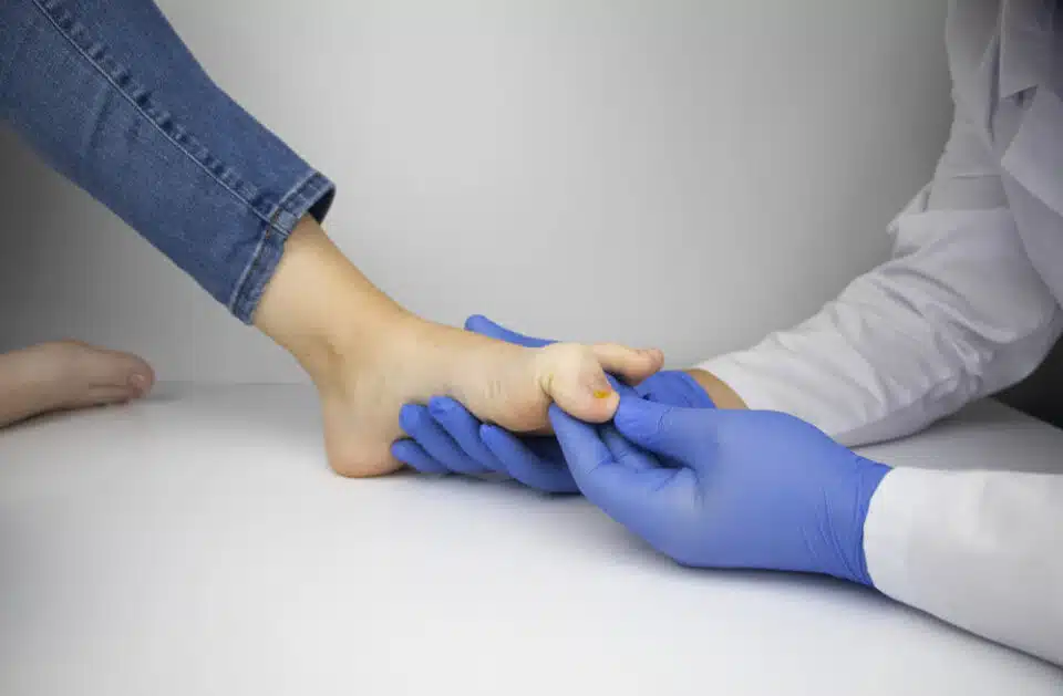 Foot care specialist with gloves inspecting female discoloured toenail