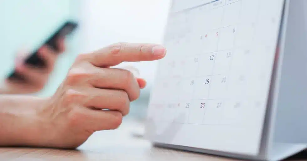 Close up view of finger pointing at calendar, foreground view of person holding their phone