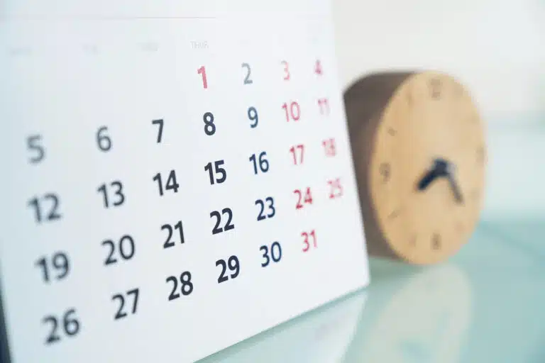 close up of calendar next to small wooden clock