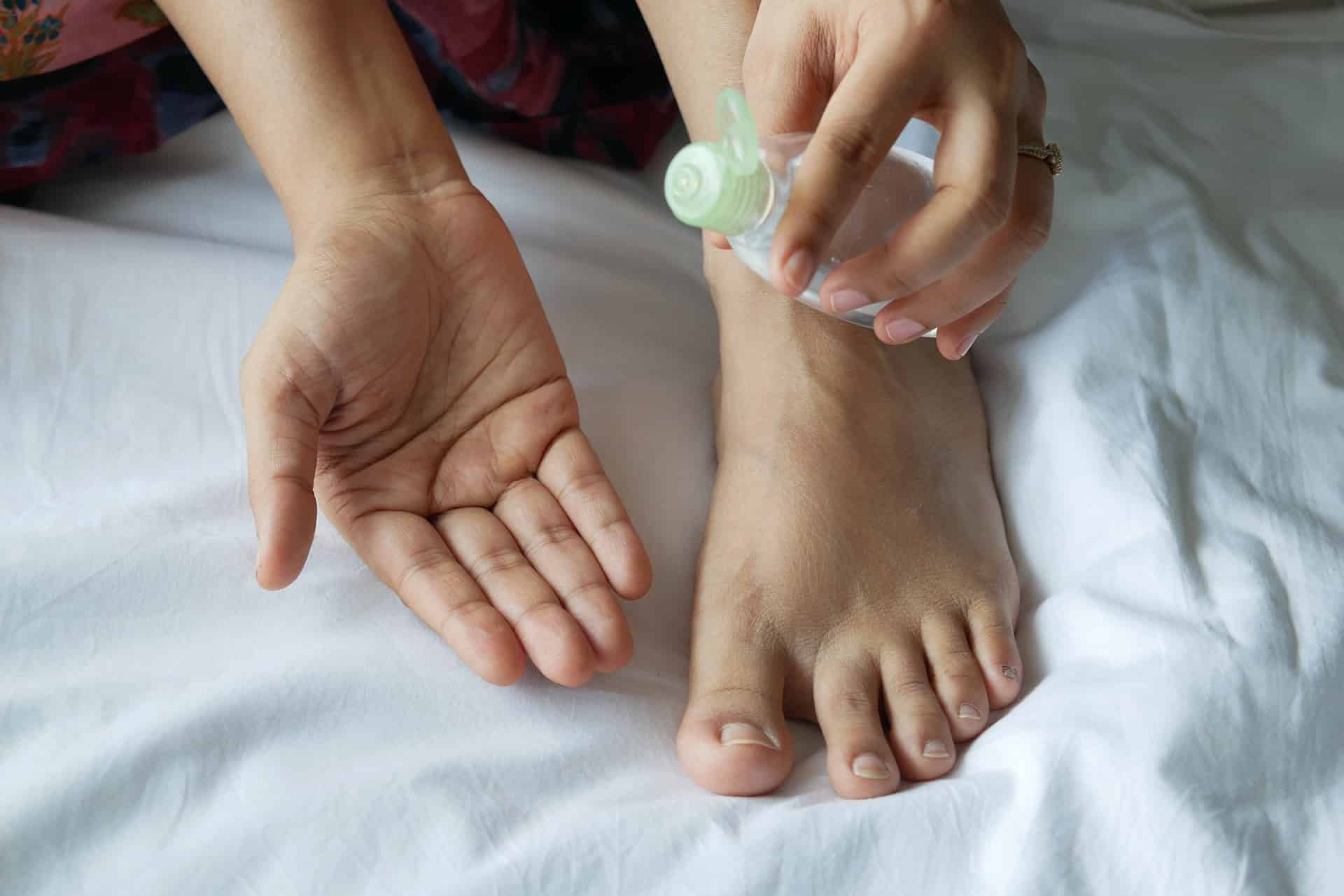 A person holding a bottle of moisturizer about to apply lotion to their legs