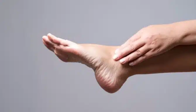 Photo of ankle with hand touching it