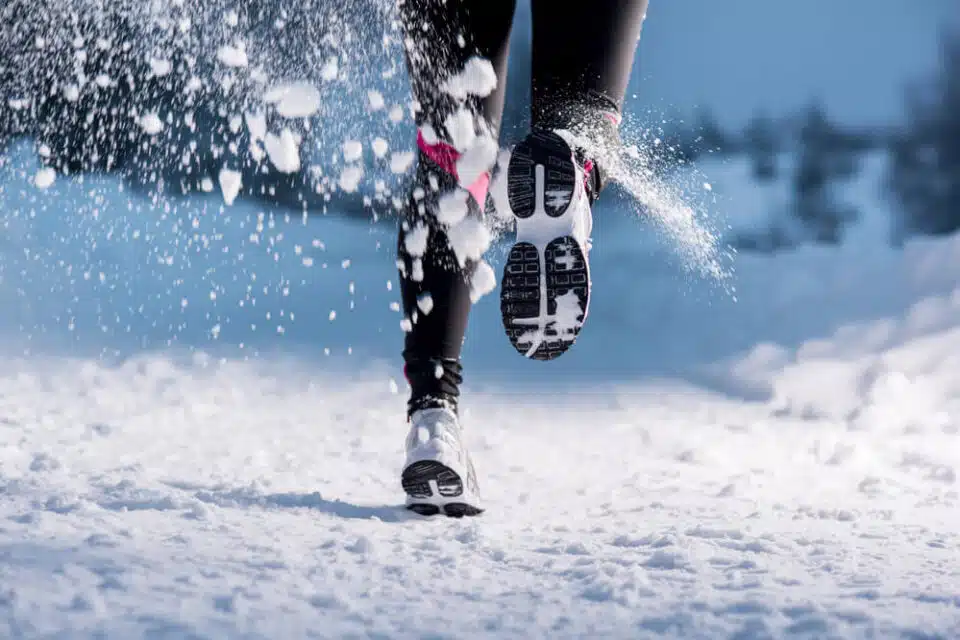 person running on winter trail one foot lifted in motion