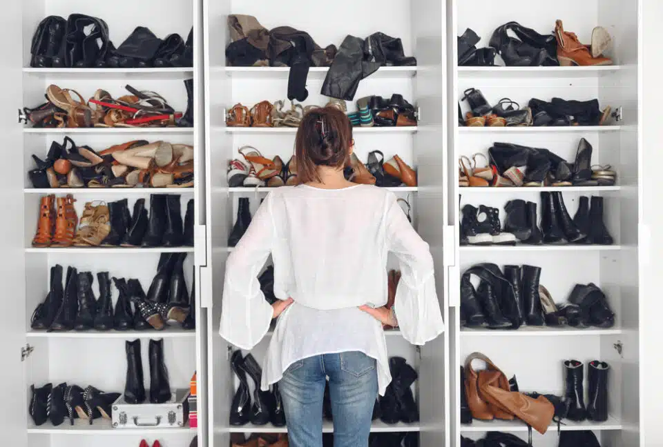 woman standing in front of several shelves filled with different shoe types