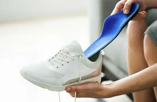 Person putting orthotic into shoe