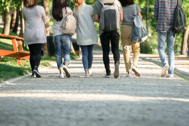 Background view of young adults walking on foot path