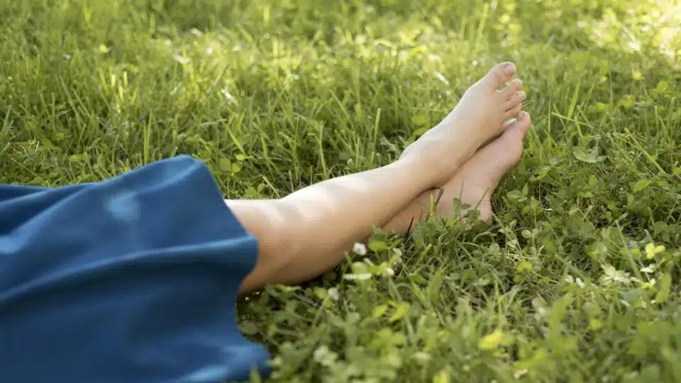 Person lying in grass with crossed feet and blue skirt