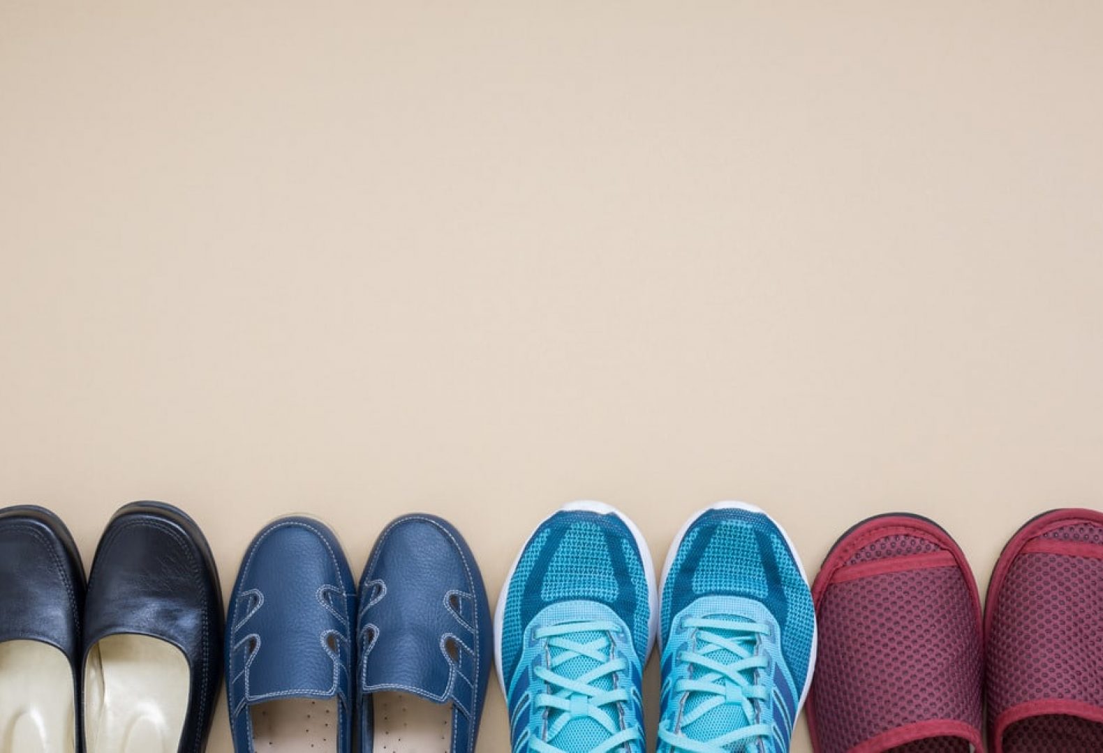 four different pairs of shoes lined up in front of beige background