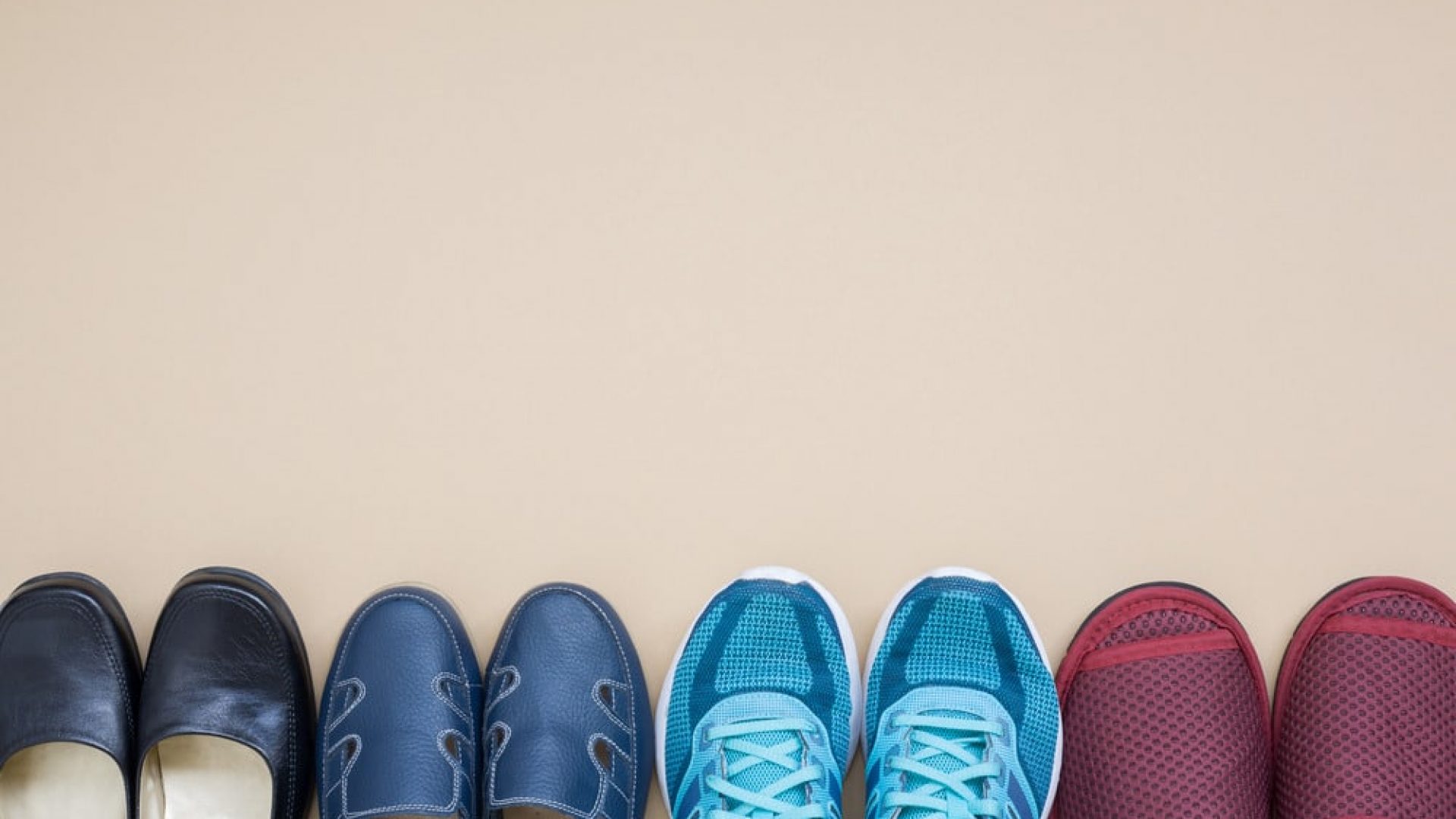 four different pairs of shoes lined up in front of beige background