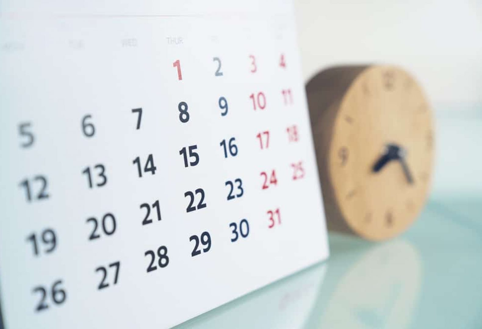 close up of calendar next to small wooden clock