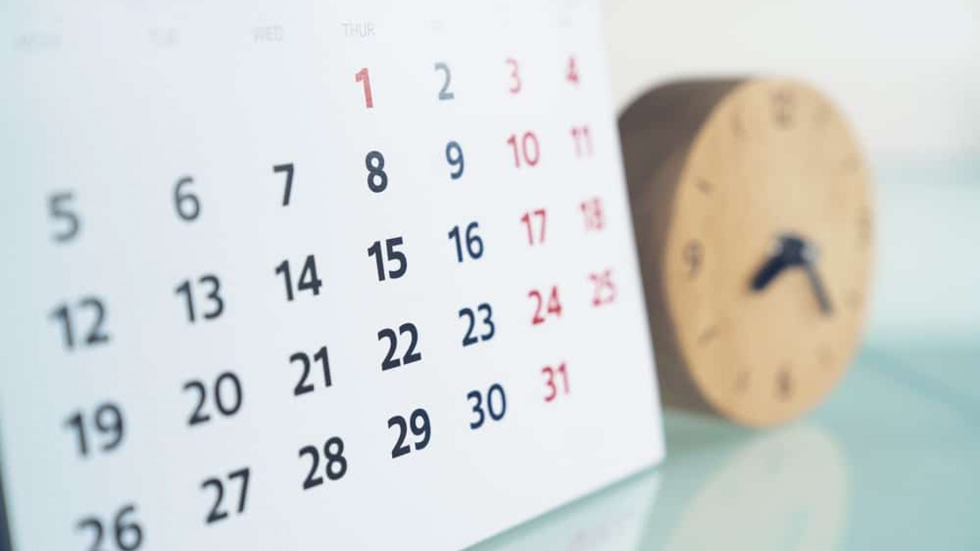 close up of calendar next to small wooden clock