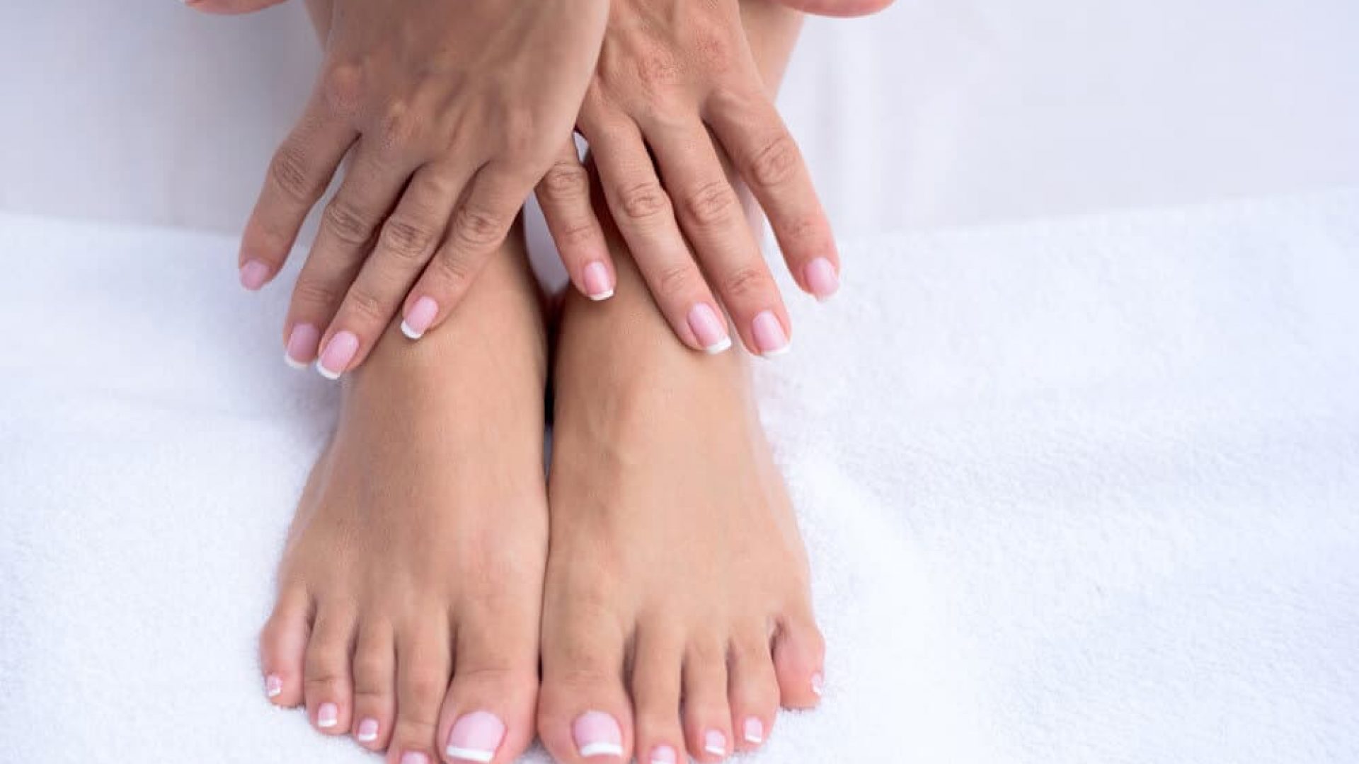 Woman close up of just fingernails and toenails with white background