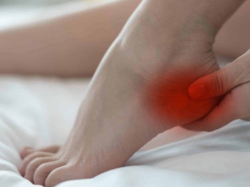 Heel Pain or plantar fasciitis concept. Hand on foot as suffer from inflammation feet problem of Sever's Disease or calcaneal apophysitis.