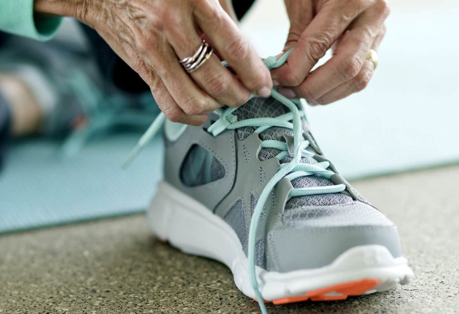 Senior woman lacing up trainers, close up.