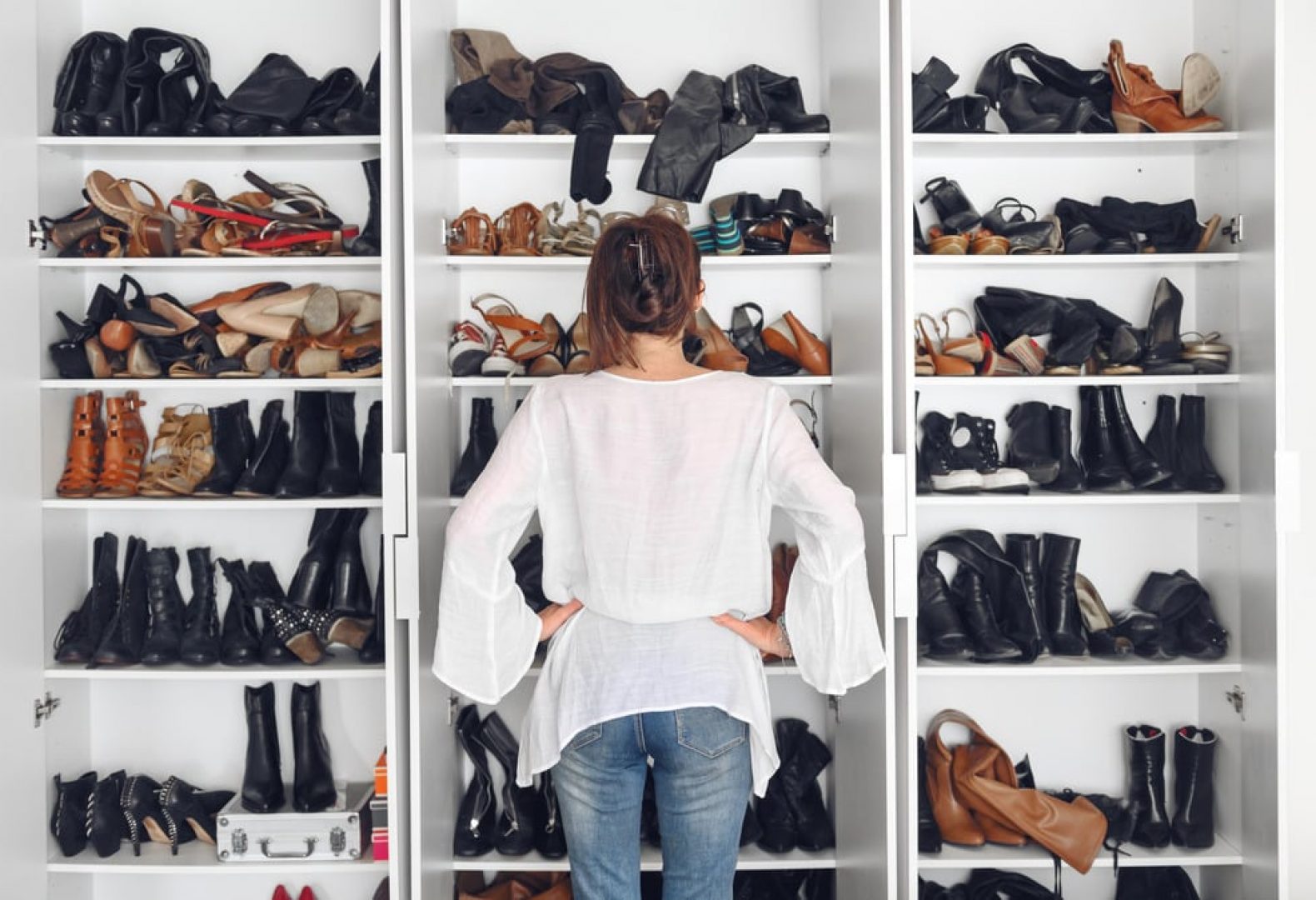 woman standing in front of several shelves filled with different shoe types