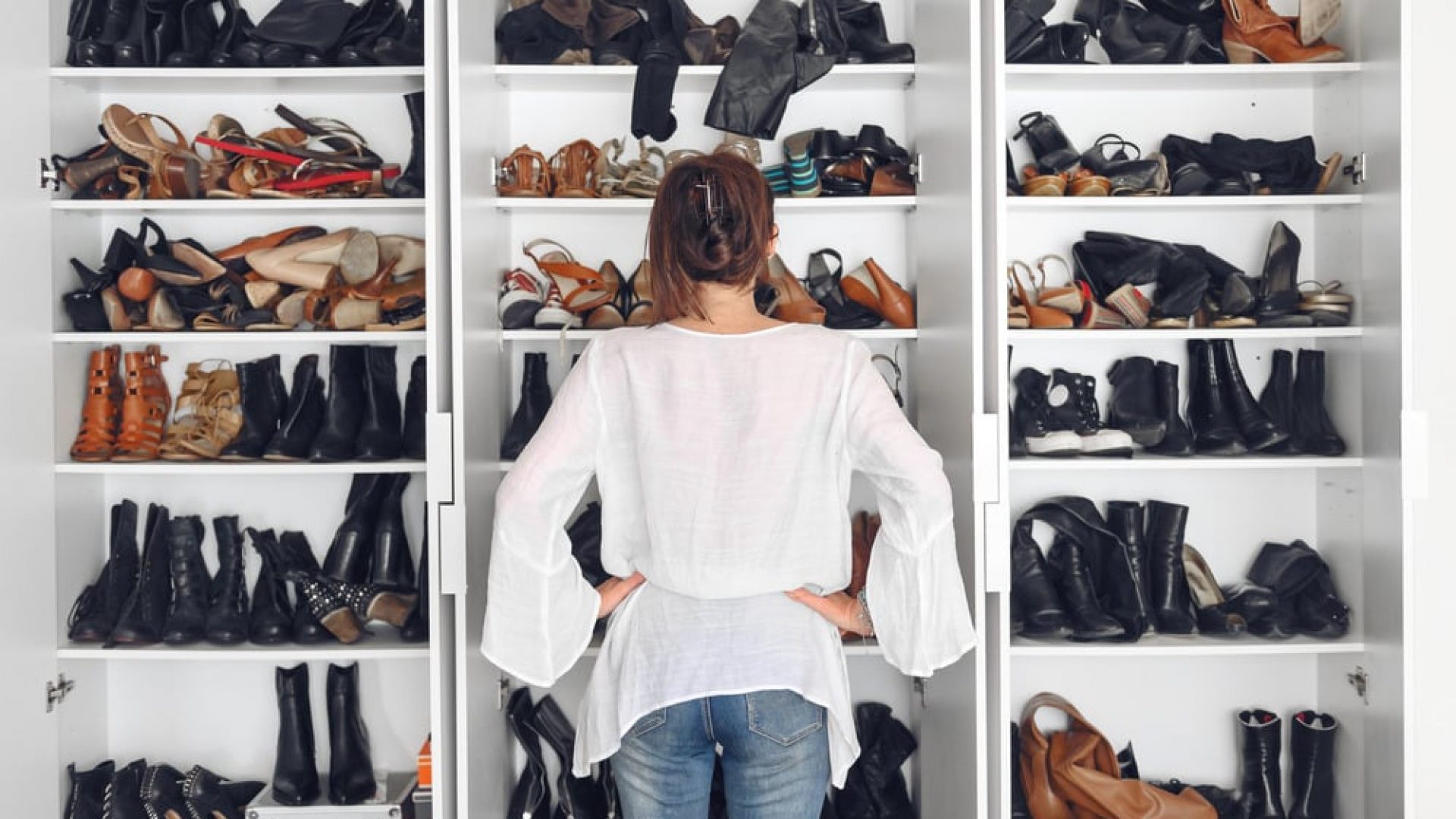 woman standing in front of several shelves filled with different shoe types