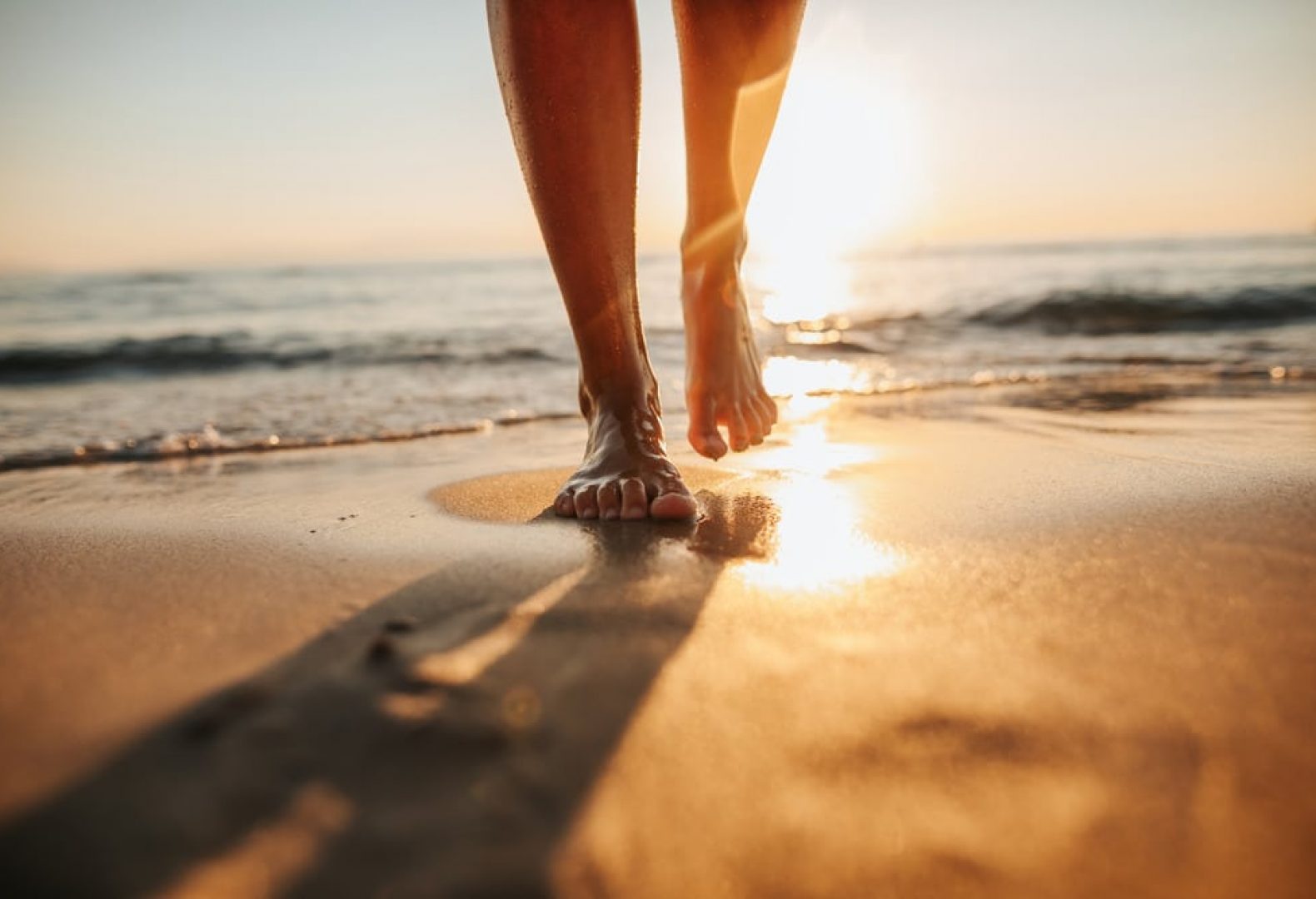 Person walking down the beach close up of bare feet on a sunny day