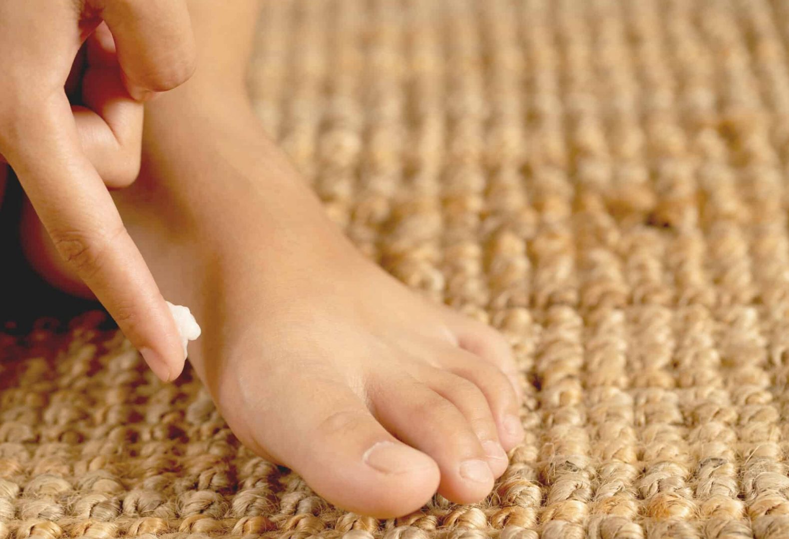 Person applying small amount of foot cream to foot