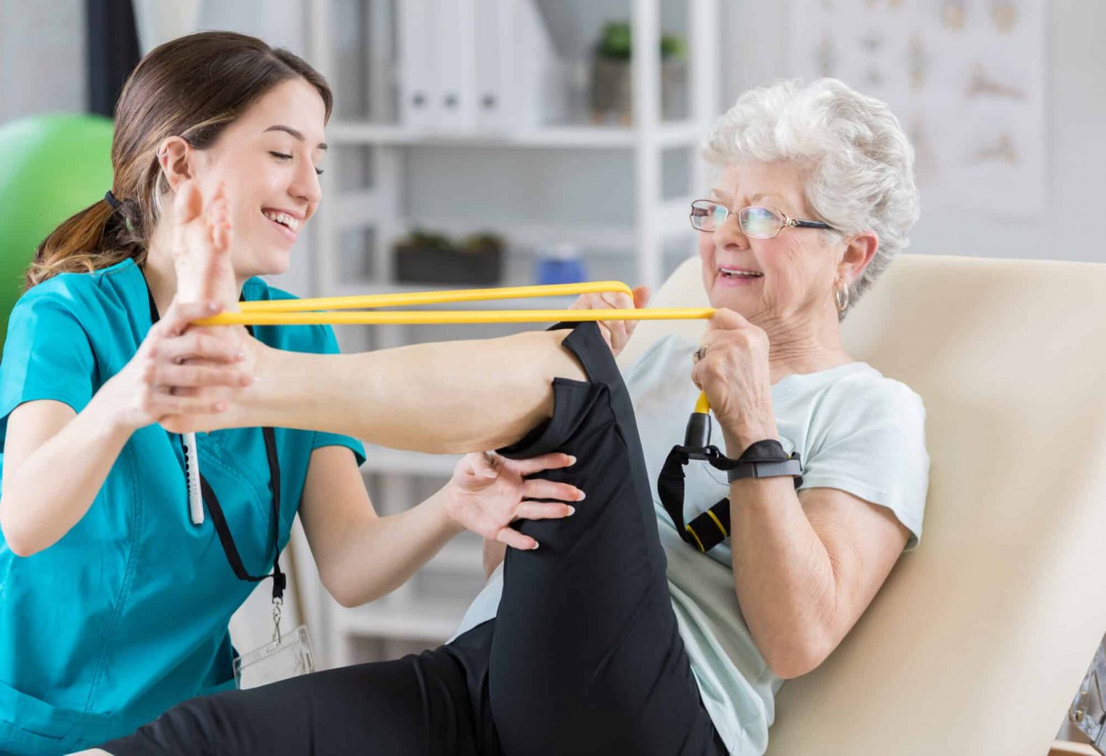 foot specialist showing senior woman how to use band for foot exercises