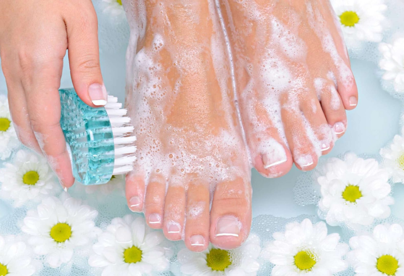 Close up of female feet in bath gently scrubbing the feet and practicing foot hygiene