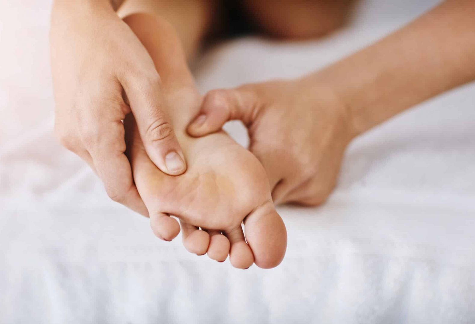 performing foot massage technique between foot's arch and ball of the foot