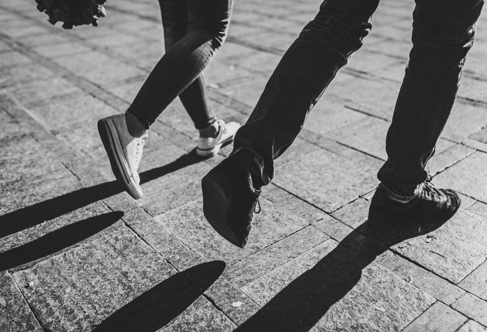 Black and white photo of two people walking with an emphasis on footwear