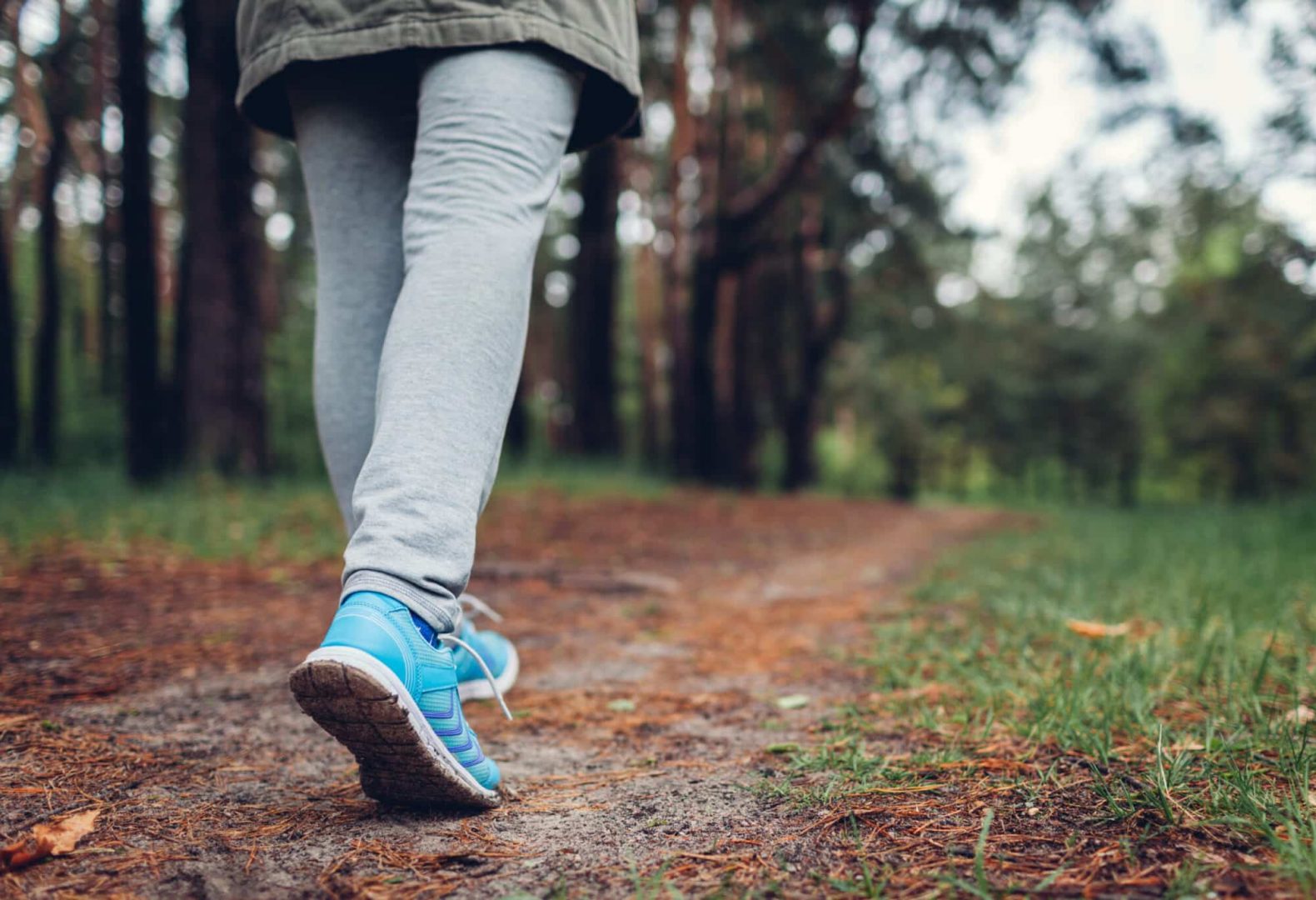 Woman walking down an outdoor trail in walking shoes