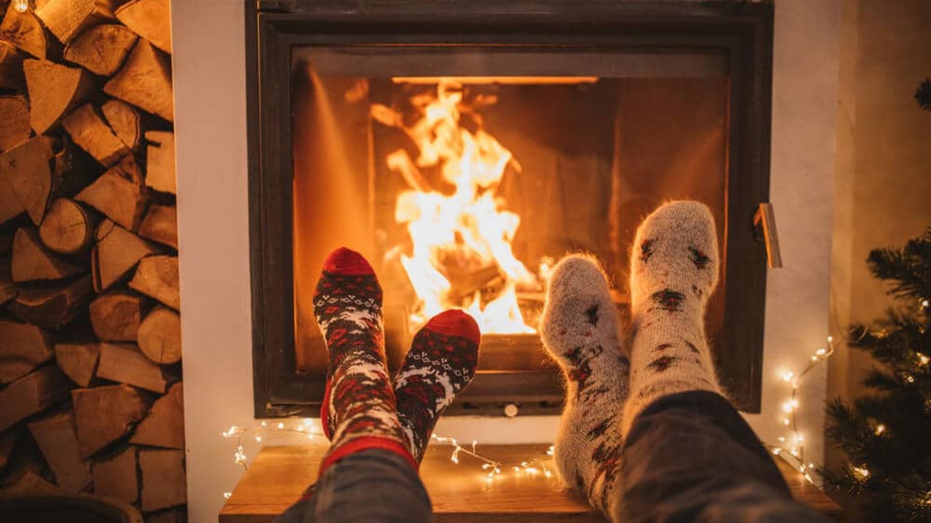 cozy fireplace dimly lit with two pairs of feet next to it wearing wool socks