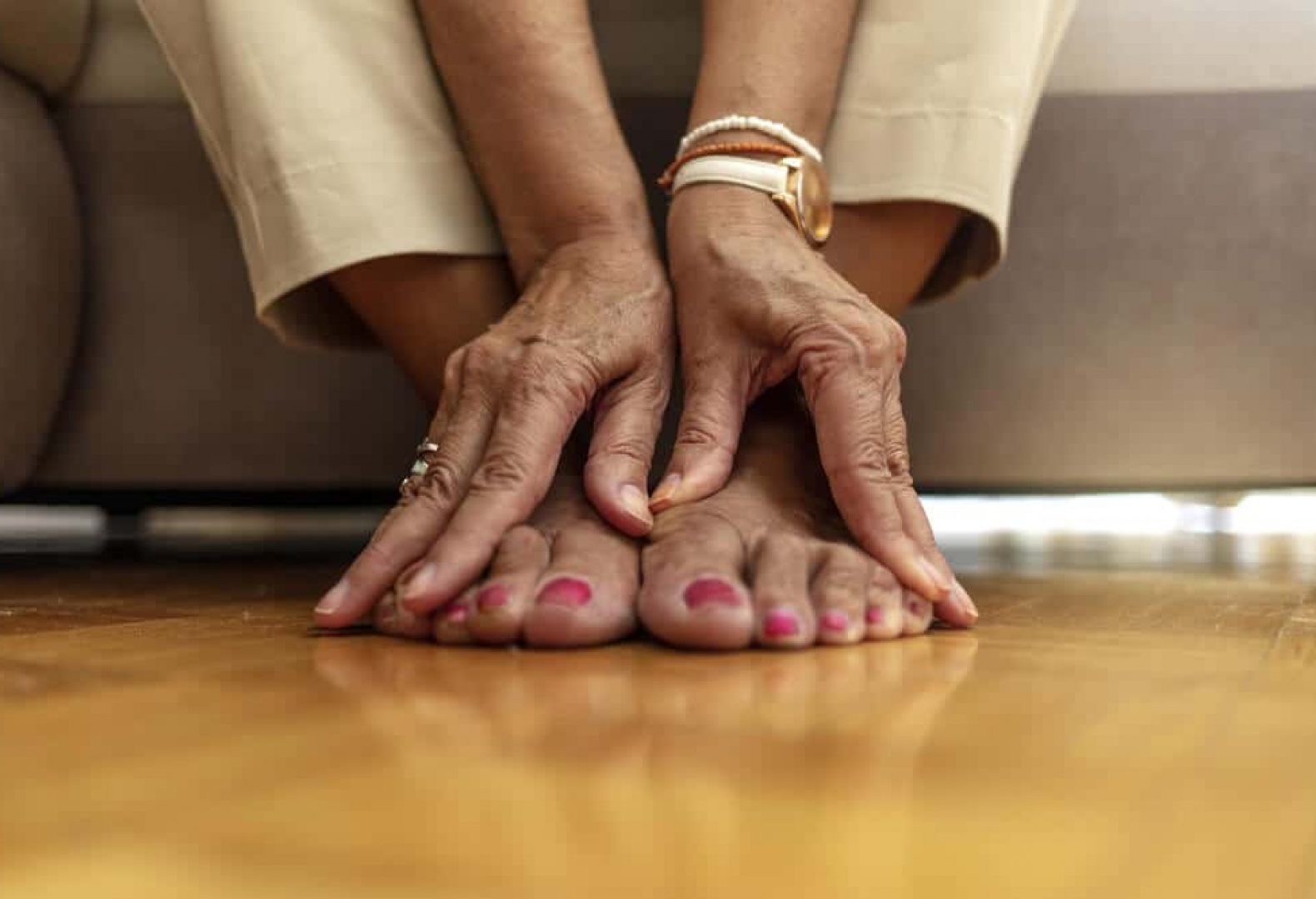 older woman feet with red toenails and her hands placed over feet