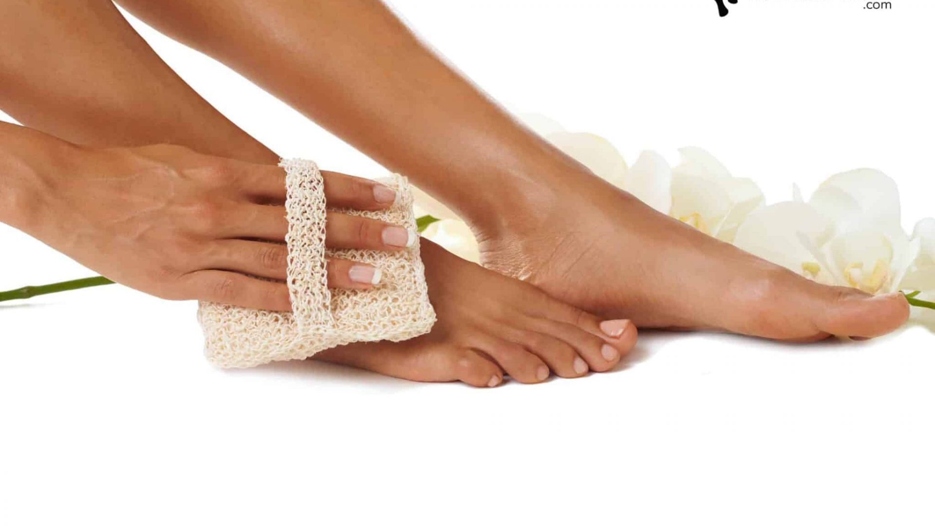 Cropped view of feet being scrubbed with a loofah and an orchid in the background