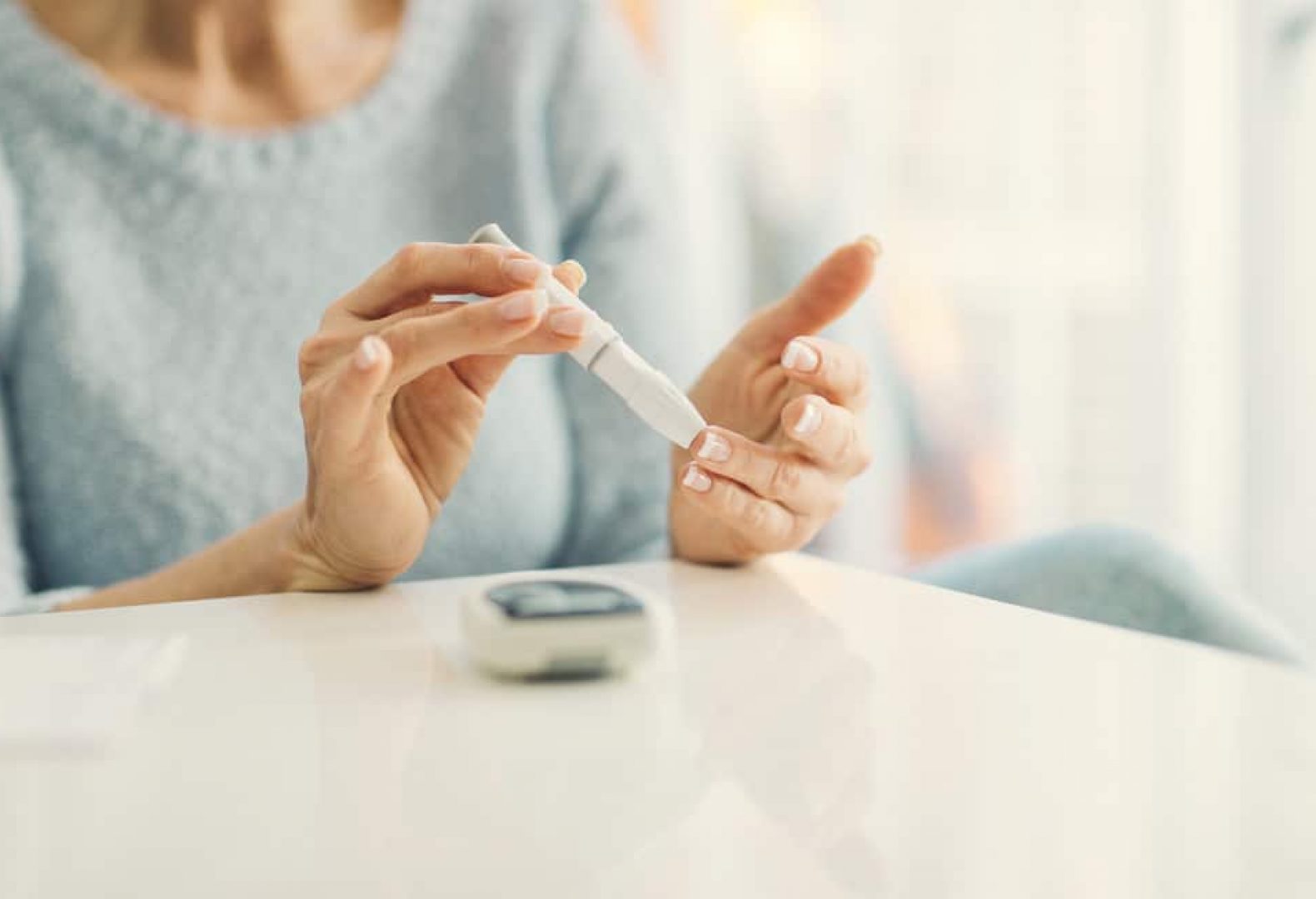 View of woman with blue sweater testing her blood sugar levels