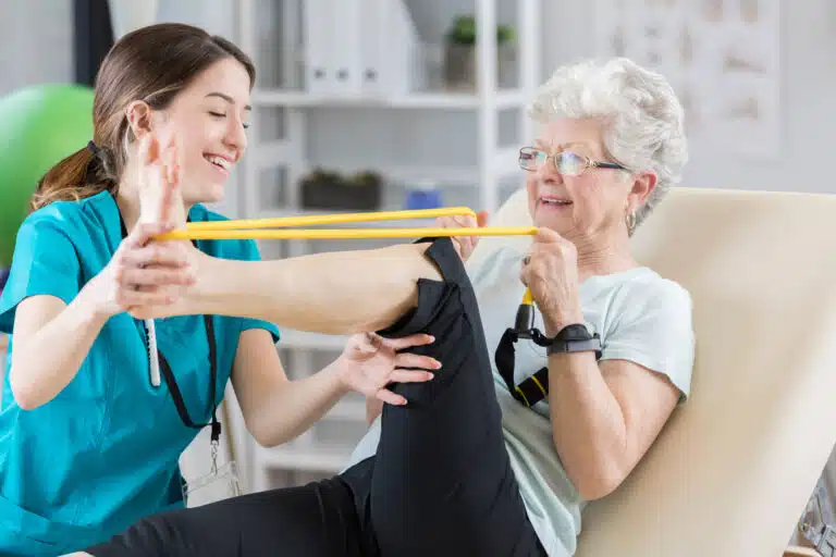 foot specialist showing senior woman how to use band for foot exercises