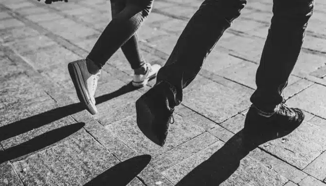 Black and white photo of two people walking with an emphasis on footwear