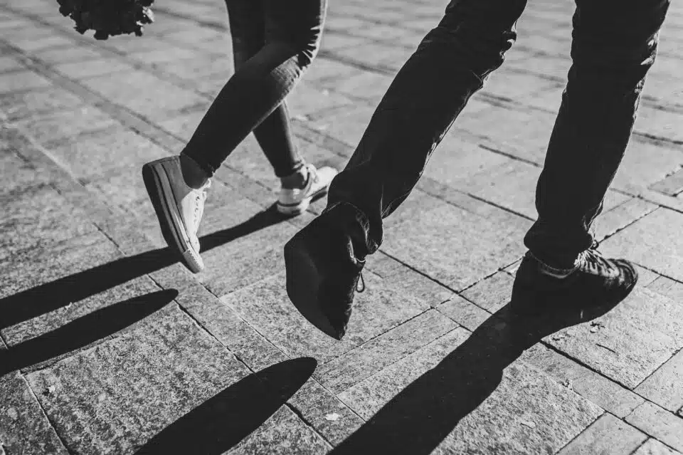 Black and white photo of two people walking with an emphasis on footwear