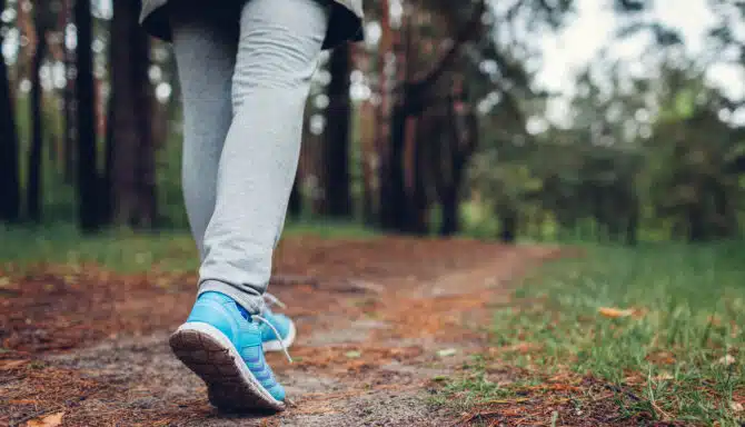 Woman walking down an outdoor trail in walking shoes