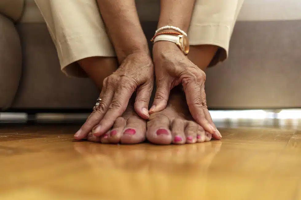 female feet with red painted toenails and hands on top of them 