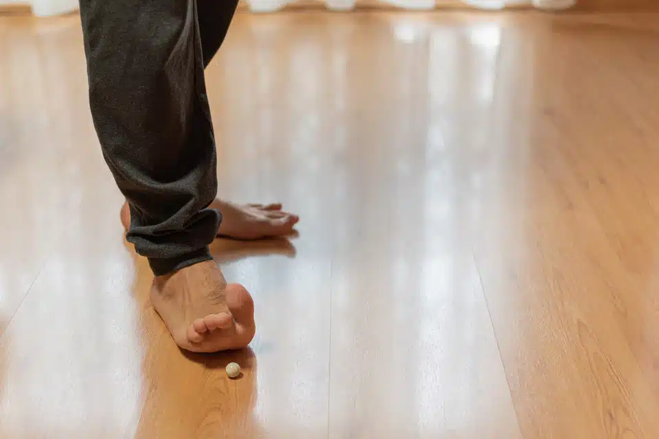 Bottom of the legs and feet view of Person wearing black pants performing toe exercises with a small ball