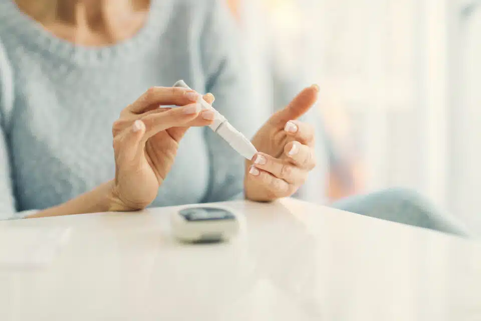 View of woman with blue sweater testing her blood sugar levels