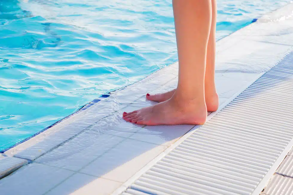 person standing at the side of the pool showing just feet and legs