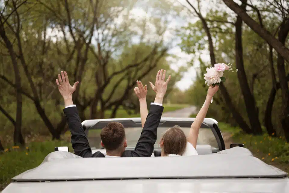 just married couple view from the back throwing their hands up in the air