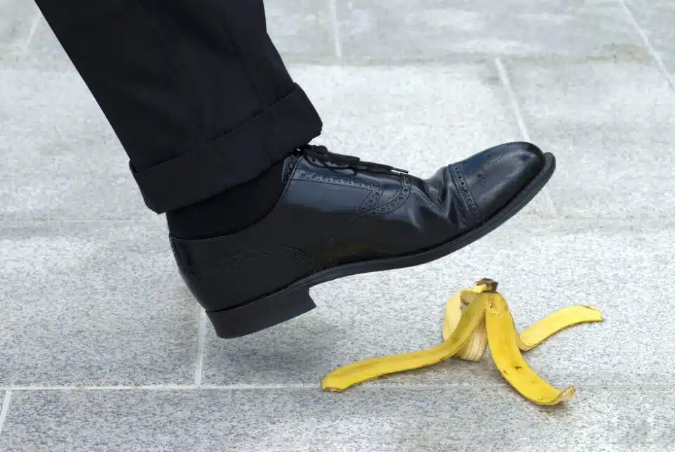 Dress shoe on tiled walkway about to slip on a banana peel