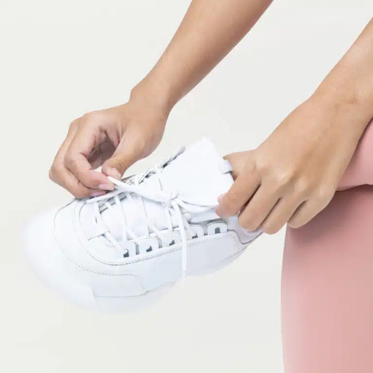 Woman tying up white trainers shoe laces