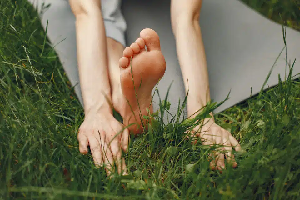 bright green grass with two arms and foot with yoga mat